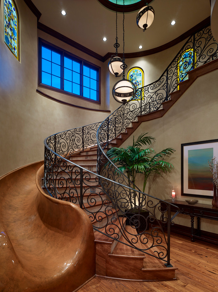 Photo of a large mediterranean wood curved staircase in Orlando with tile risers and metal railing.