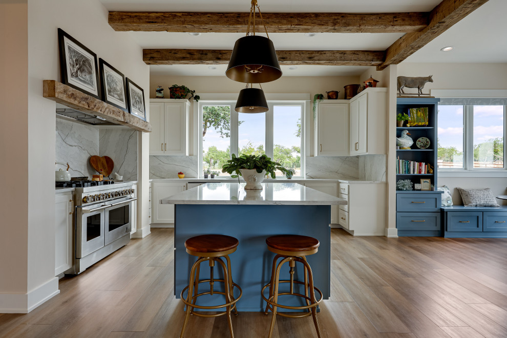 Example of a cottage l-shaped light wood floor eat-in kitchen design in Austin with white cabinets, marble countertops, marble backsplash, stainless steel appliances and an island