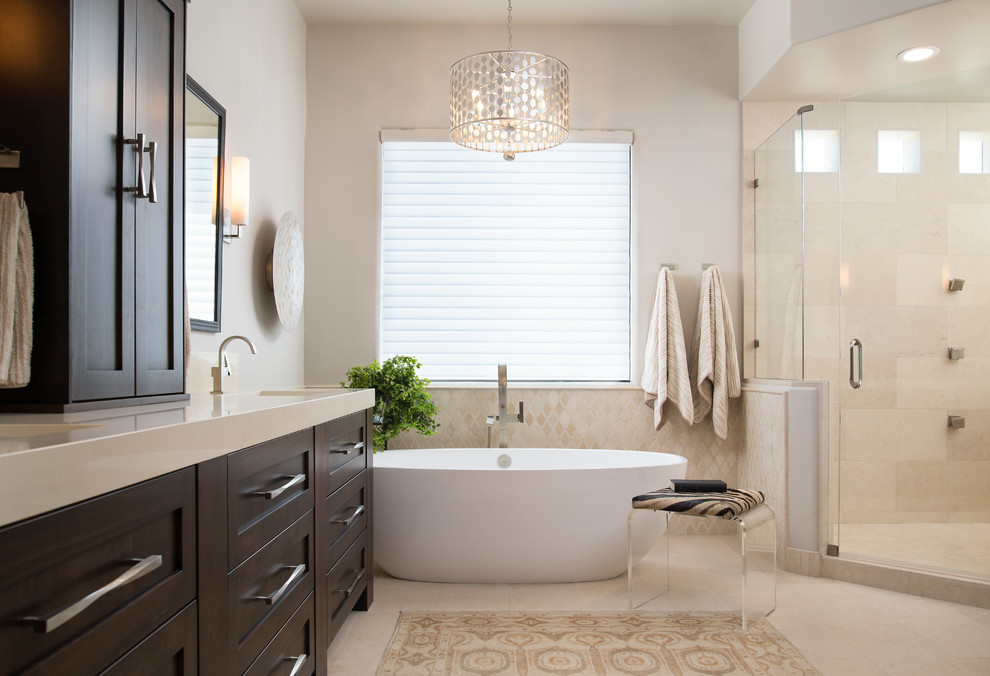 Inspiration for a mid-sized transitional master beige tile and stone tile limestone floor and beige floor freestanding bathtub remodel in Phoenix with shaker cabinets, dark wood cabinets, gray walls, an undermount sink, quartz countertops, a hinged shower door and beige countertops