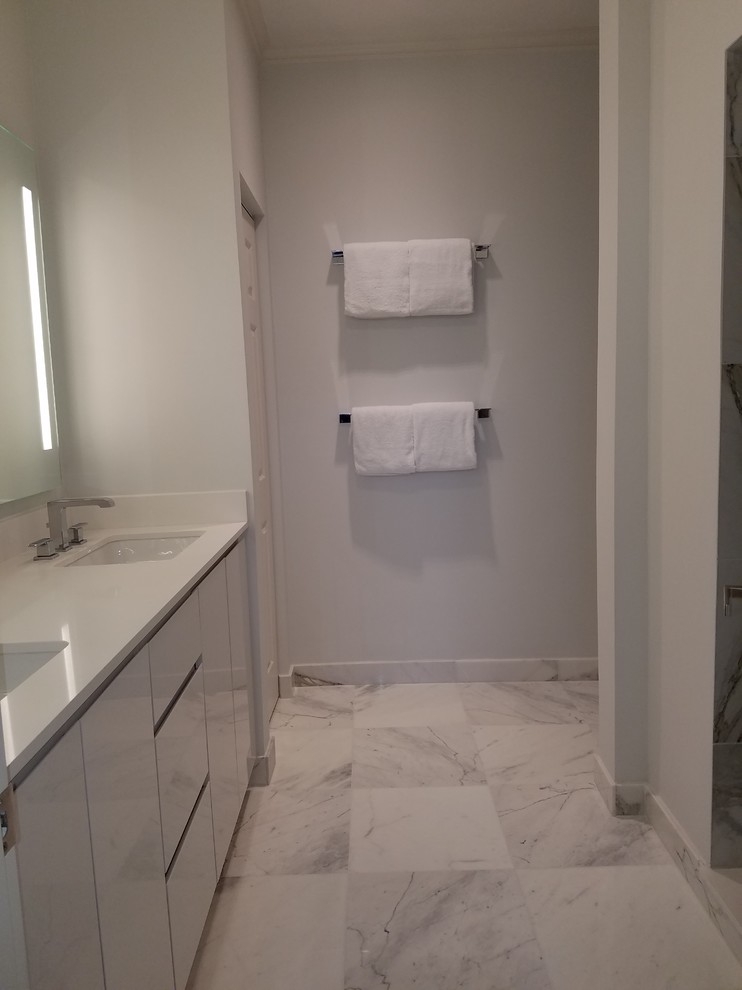 Small transitional master white tile and marble tile marble floor and white floor double shower photo in Miami with flat-panel cabinets, white cabinets, a one-piece toilet, blue walls, an undermount sink, quartz countertops and a hinged shower door