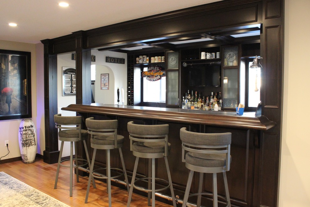 Design ideas for a mid-sized traditional u-shaped seated home bar in Calgary with an undermount sink, raised-panel cabinets, dark wood cabinets, laminate benchtops, grey splashback and medium hardwood floors.