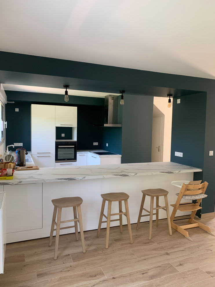 Large u-shaped open plan kitchen in Lyon with a submerged sink, white cabinets, marble worktops, white splashback, marble splashback, integrated appliances, ceramic flooring, no island and white worktops.