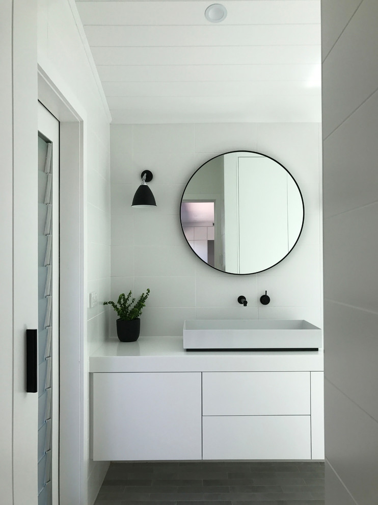 This is an example of a contemporary wet room bathroom in Sydney with a one-piece toilet, white tile, ceramic tile, white walls, ceramic floors, grey floor and an open shower.
