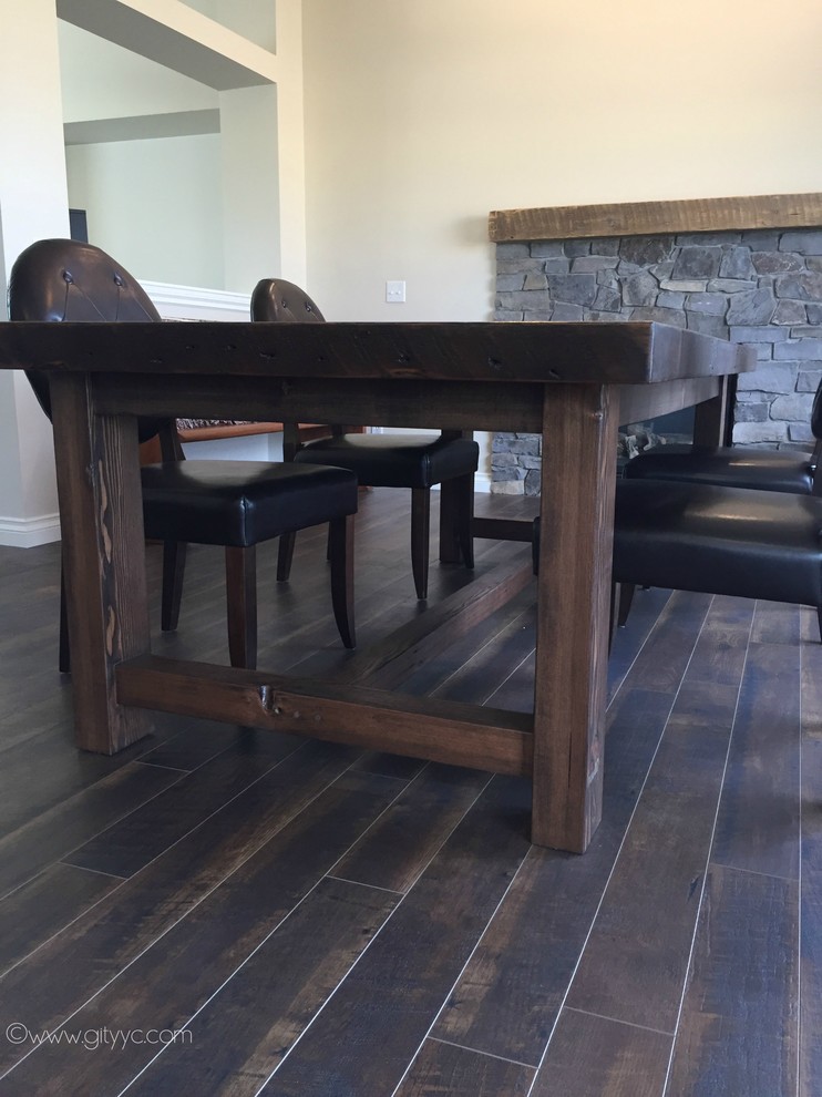 Example of a mid-sized mountain style laminate floor and black floor home design design in Calgary with beige walls, a standard fireplace and a stone fireplace