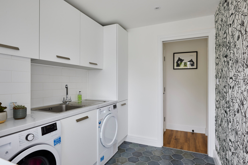 This is an example of a mid-sized modern laundry room in Kent with an undermount sink, flat-panel cabinets, white cabinets, quartzite benchtops, blue splashback, glass sheet splashback, medium hardwood floors, brown floor and white benchtop.