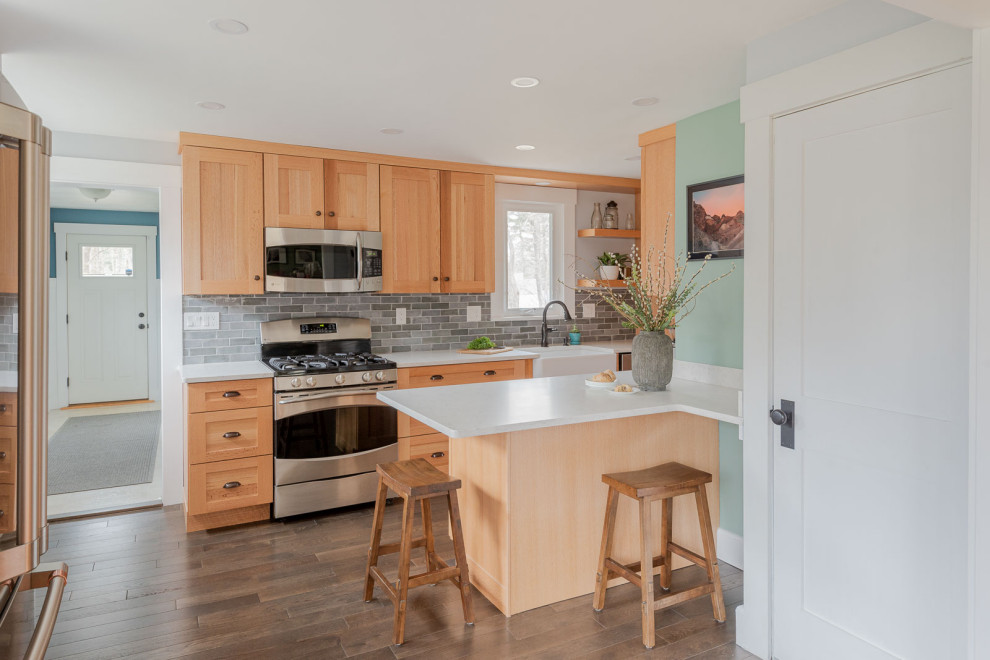 Enclosed kitchen - mid-sized transitional galley medium tone wood floor and brown floor enclosed kitchen idea in Boston with a farmhouse sink, shaker cabinets, light wood cabinets, quartz countertops, gray backsplash, ceramic backsplash, stainless steel appliances and white countertops
