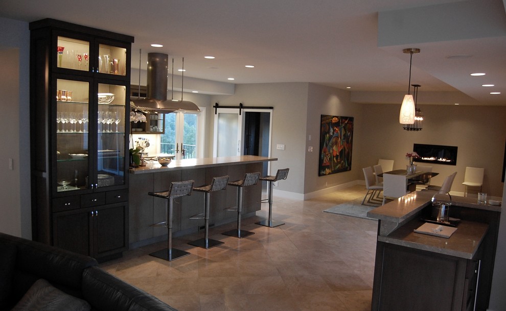 Inspiration for a mid-sized transitional galley travertine floor open concept kitchen remodel in Orange County with a farmhouse sink, shaker cabinets, gray cabinets, limestone countertops, beige backsplash, stone tile backsplash, stainless steel appliances and a peninsula