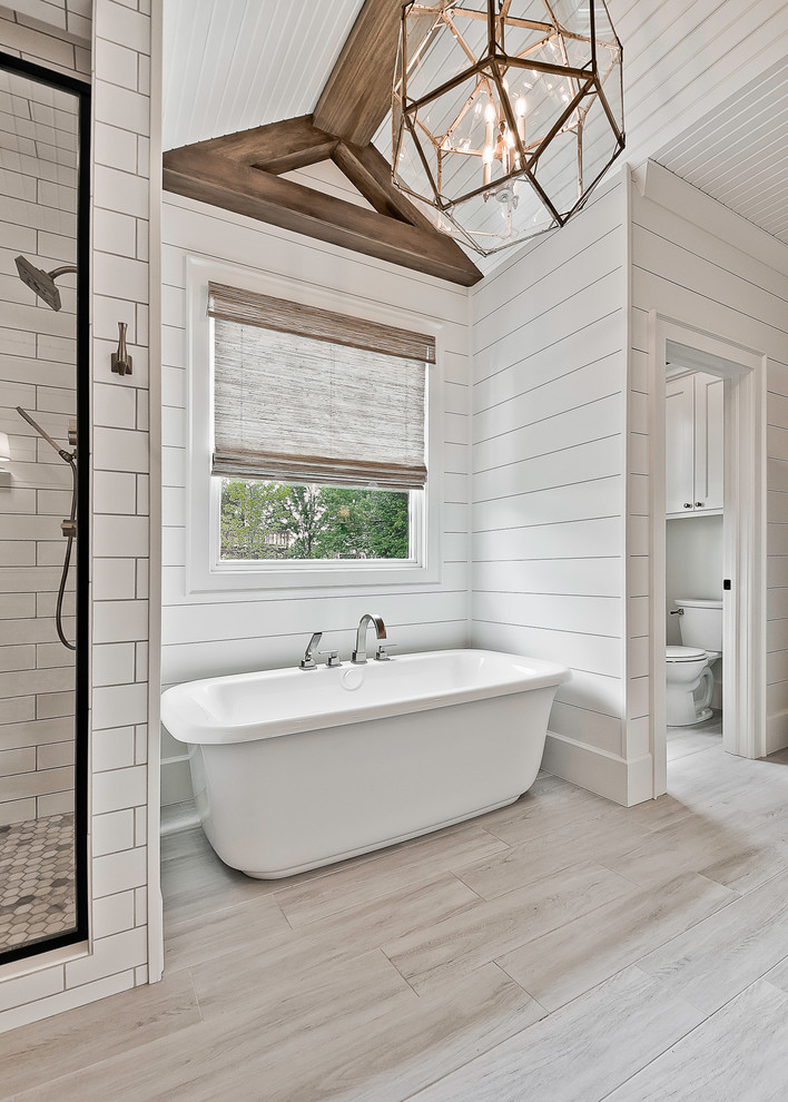 This is an example of a large country master bathroom in Other with a freestanding tub, an alcove shower, a two-piece toilet, white tile, porcelain tile, white walls, ceramic floors and grey floor.