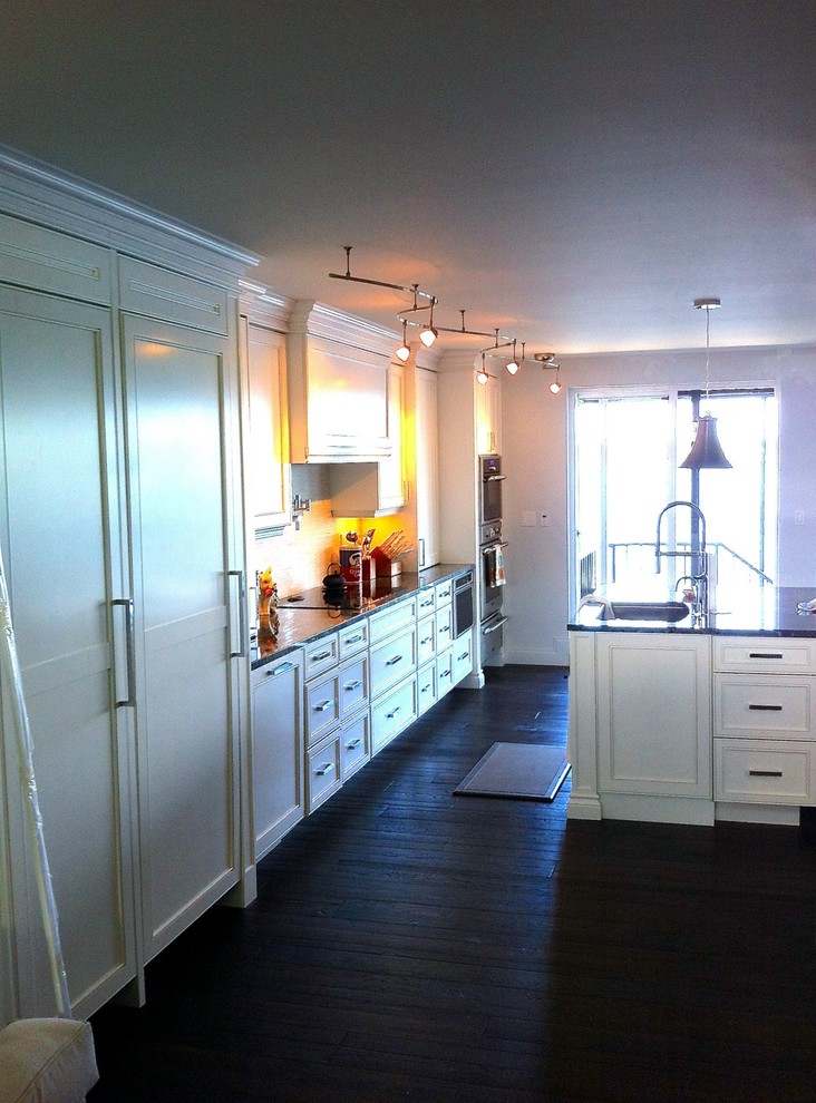 Inspiration for a large transitional single-wall dark wood floor and brown floor open concept kitchen remodel in Miami with a single-bowl sink, shaker cabinets, white cabinets, granite countertops, white backsplash, stone tile backsplash, stainless steel appliances and an island