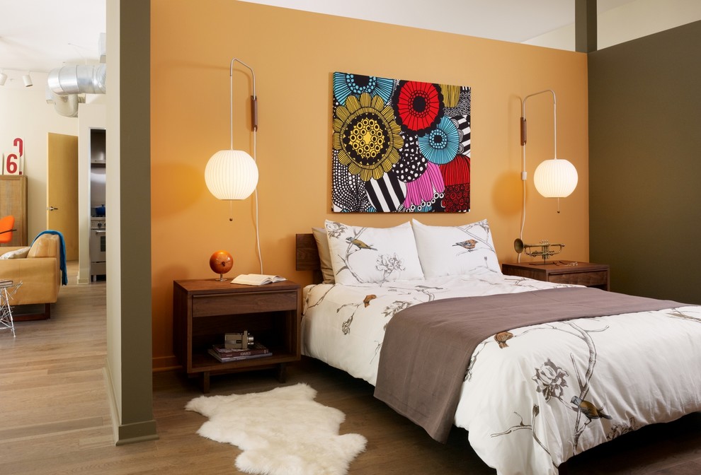 Inspiration for an industrial bedroom in Los Angeles with orange walls and medium hardwood floors.