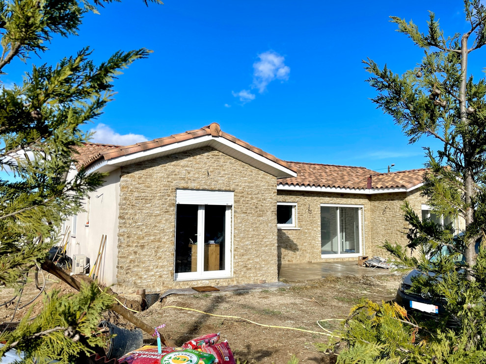Cette photo montre une grande façade de maison beige méditerranéenne en pierre de plain-pied.