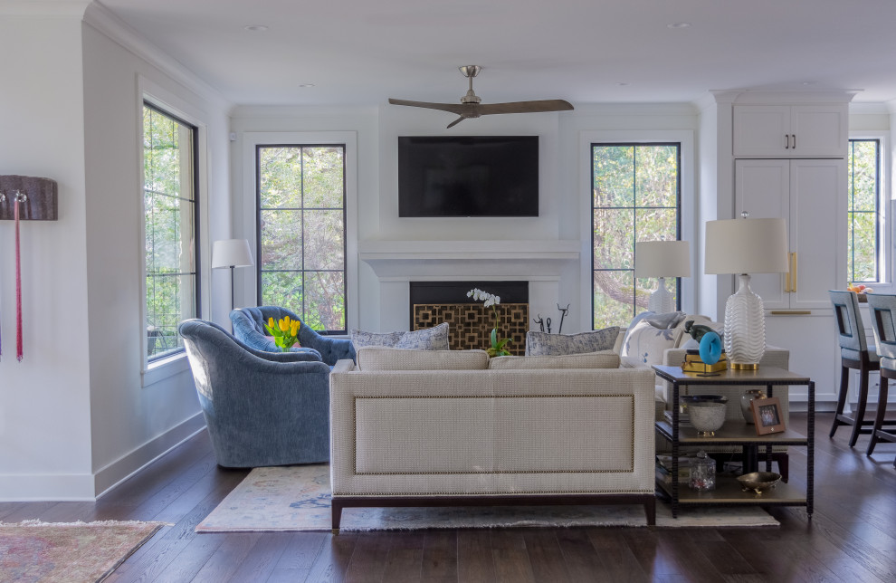 This is an example of a transitional open concept living room in Austin with white walls, dark hardwood floors, a standard fireplace, a wall-mounted tv and brown floor.