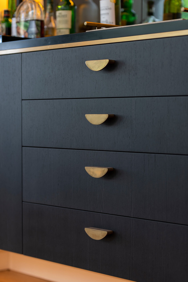 Large contemporary single-wall wet bar in Sydney with an integrated sink, flat-panel cabinets, black cabinets, solid surface benchtops, mirror splashback, light hardwood floors and black benchtop.