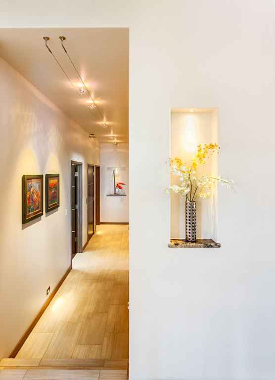 This is an example of a large contemporary hallway in Denver with white walls and ceramic floors.