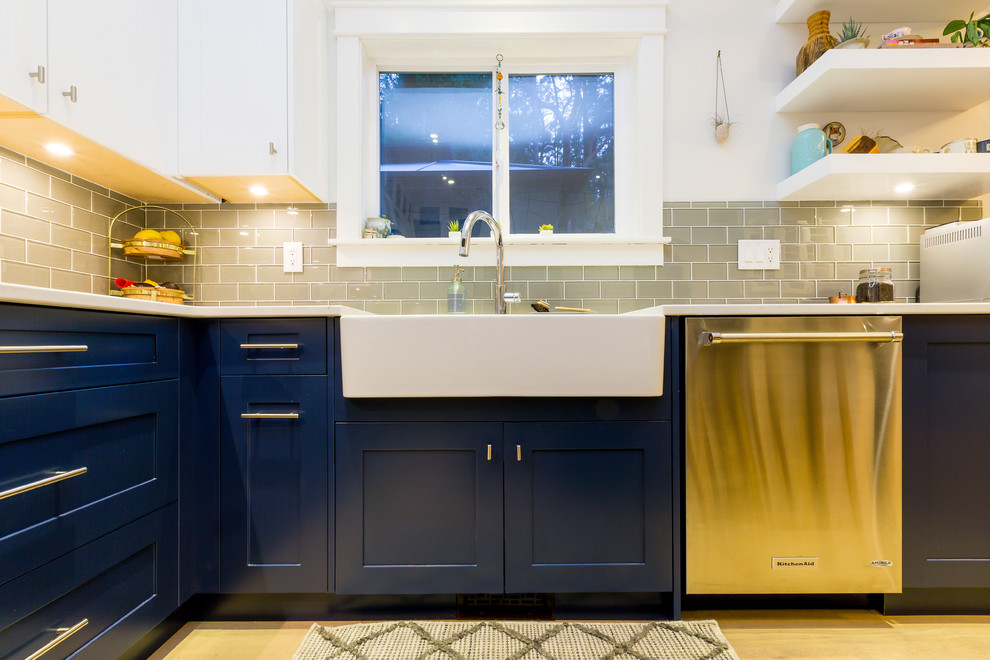 Open concept kitchen - large transitional u-shaped light wood floor open concept kitchen idea with a farmhouse sink, shaker cabinets, blue cabinets, quartz countertops, gray backsplash, glass tile backsplash, stainless steel appliances, an island and white countertops