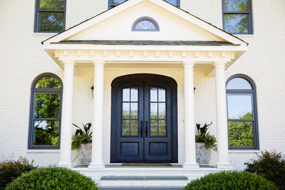 Photo of a large traditional front door in Charlotte with white walls, a double front door, a black front door and brick walls.