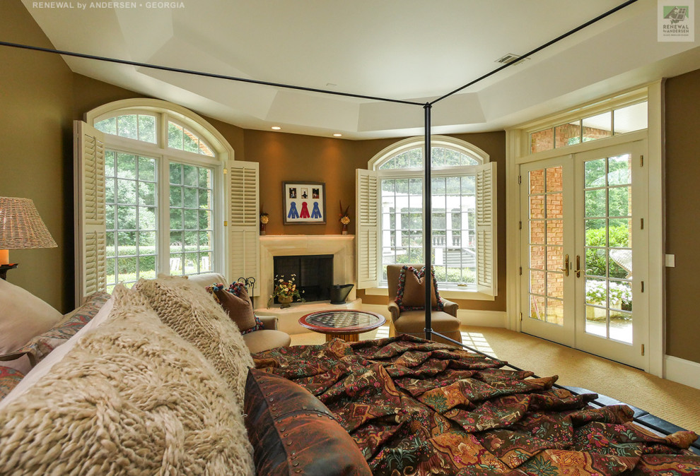 Großes Hauptschlafzimmer mit brauner Wandfarbe, Teppichboden, Kamin, verputzter Kaminumrandung, beigem Boden und Kassettendecke in Atlanta