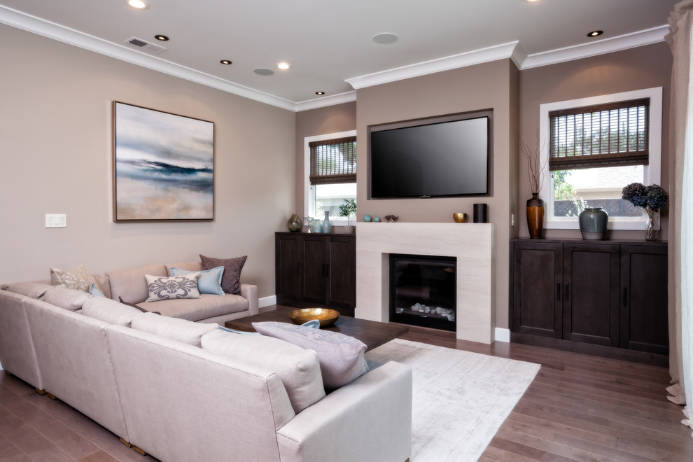 Inspiration for a mid-sized transitional enclosed living room in San Francisco with beige walls, medium hardwood floors, a standard fireplace, a stone fireplace surround, a wall-mounted tv and brown floor.