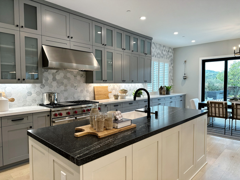 Transitional brown floor kitchen photo in Orange County with a farmhouse sink, granite countertops, two islands and black countertops
