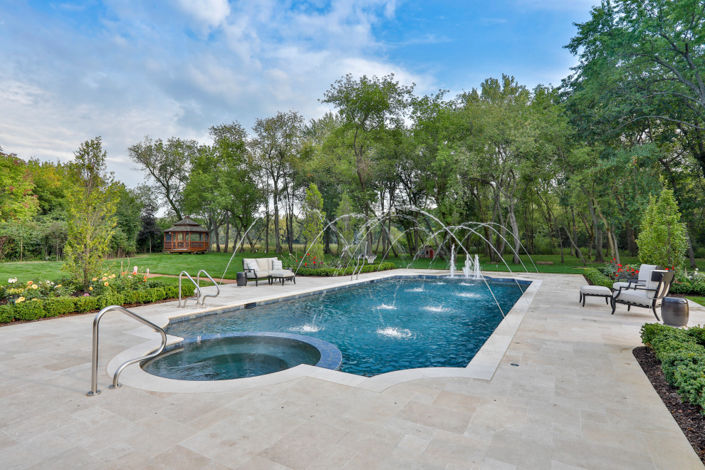 This is an example of a mid-sized mediterranean backyard custom-shaped lap pool in Chicago with a hot tub and natural stone pavers.