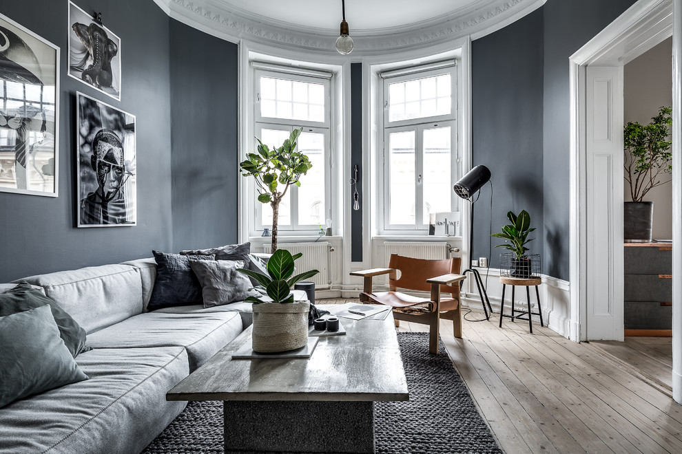 Photo of a scandinavian living room in Stockholm with black walls, light hardwood floors and beige floor.
