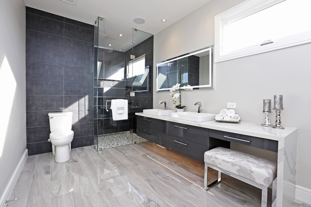 Photo of a large contemporary master bathroom in Toronto with an alcove shower, a one-piece toilet, grey walls, ceramic floors, an integrated sink, marble benchtops, grey floor, a hinged shower door, white benchtops, a freestanding tub, gray tile and ceramic tile.