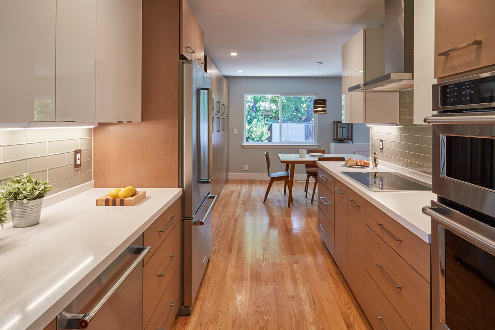 Photo of a small contemporary galley eat-in kitchen in San Francisco with brown cabinets, quartzite benchtops, green splashback, glass tile splashback, stainless steel appliances, no island and white benchtop.