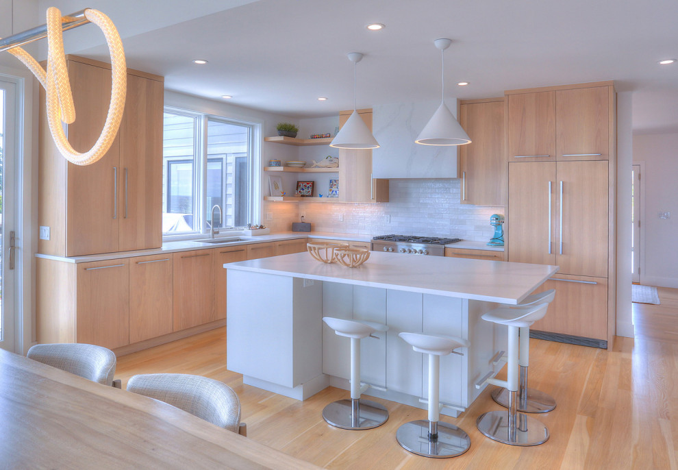 This is an example of a mid-sized scandinavian l-shaped open plan kitchen in Bridgeport with an undermount sink, flat-panel cabinets, light wood cabinets, quartz benchtops, white splashback, ceramic splashback, panelled appliances, light hardwood floors, with island, beige floor, white benchtop and vaulted.