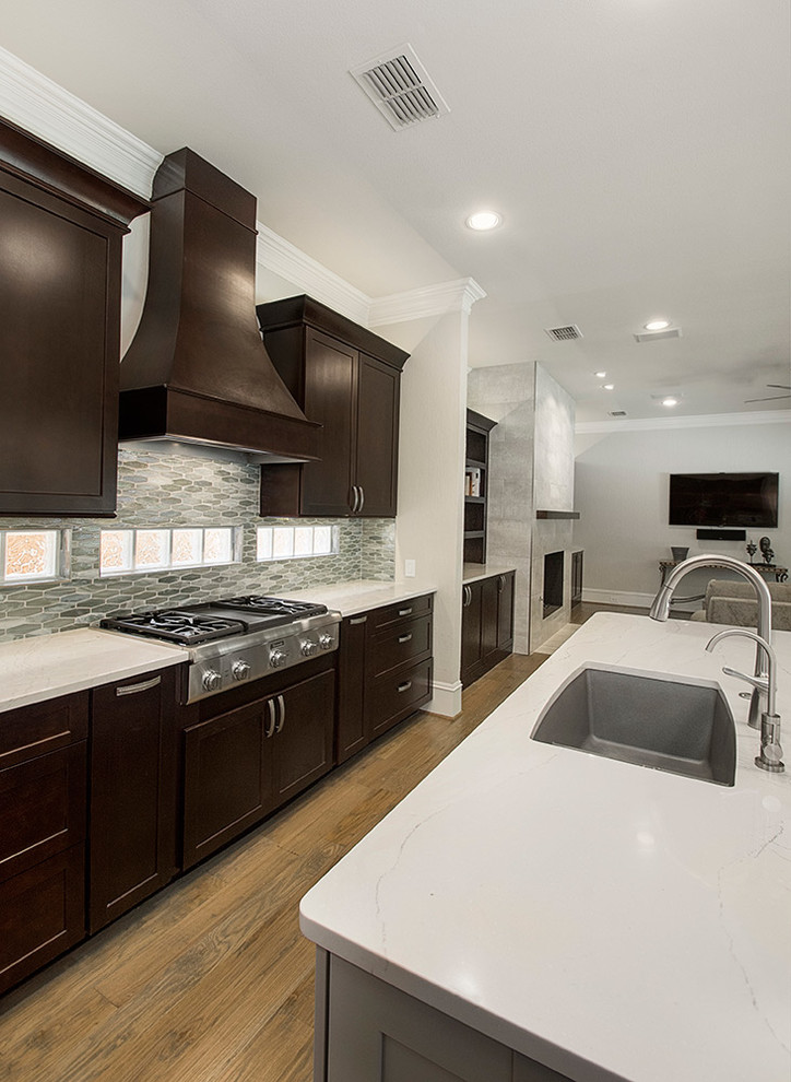 Open concept kitchen - mid-sized transitional l-shaped medium tone wood floor and brown floor open concept kitchen idea in DC Metro with an undermount sink, recessed-panel cabinets, dark wood cabinets, granite countertops, beige backsplash, ceramic backsplash, stainless steel appliances, an island and beige countertops
