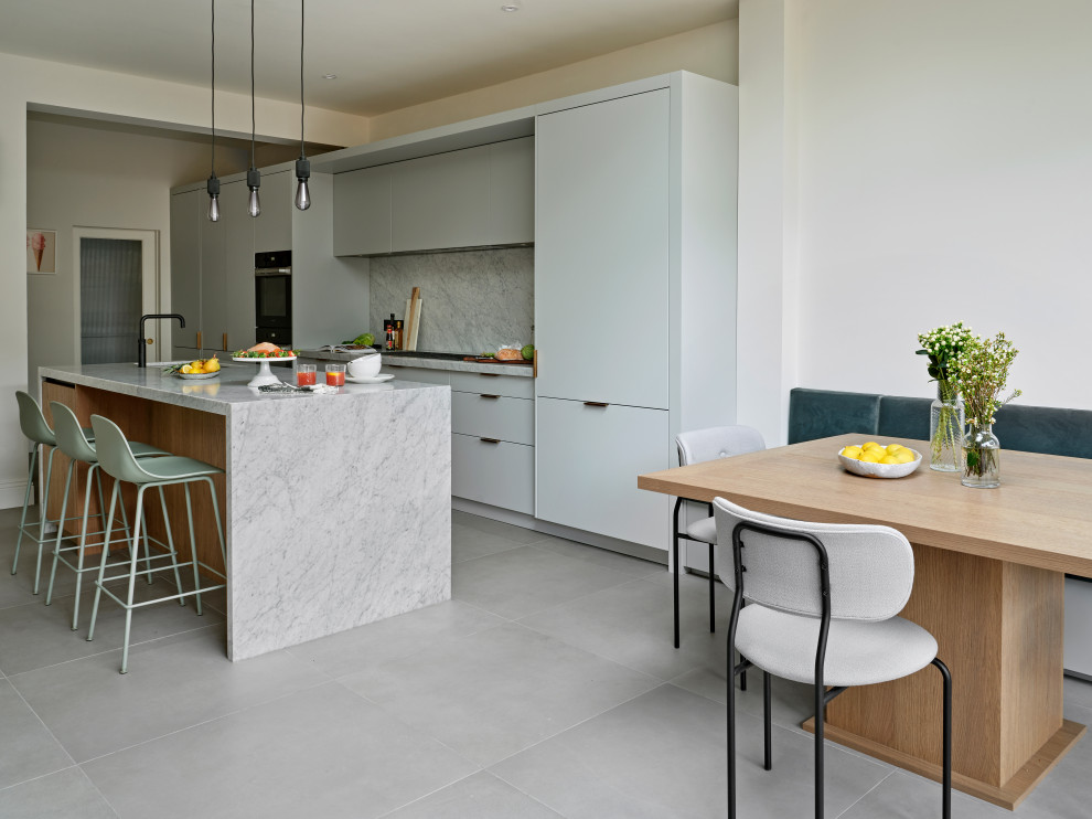 Mid-sized midcentury single-wall eat-in kitchen in London with an undermount sink, flat-panel cabinets, grey cabinets, marble benchtops, grey splashback, marble splashback, black appliances, with island and grey benchtop.