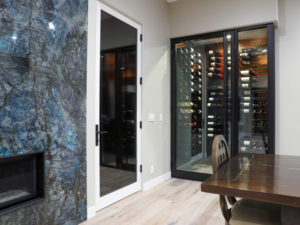 Design ideas for a small contemporary wine cellar in San Diego with light hardwood floors, display racks and beige floor.