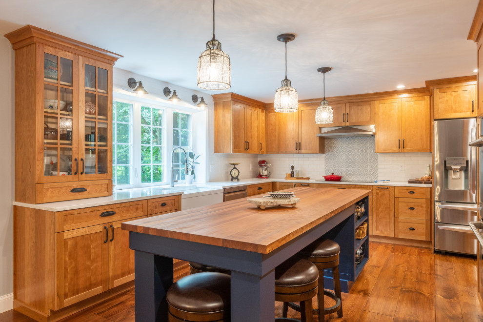 Inspiration for a large transitional medium tone wood floor enclosed kitchen remodel in Boston with a farmhouse sink, shaker cabinets, light wood cabinets, quartz countertops, white backsplash, subway tile backsplash, stainless steel appliances, an island and white countertops