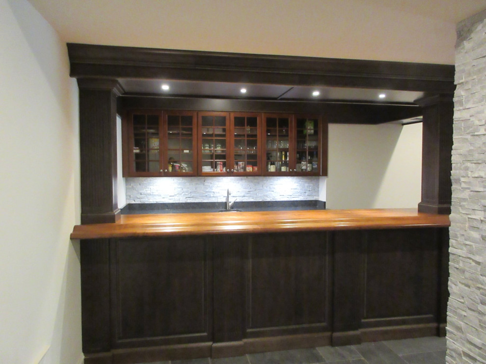 Design ideas for a mid-sized traditional galley wet bar in DC Metro with raised-panel cabinets, dark wood cabinets, wood benchtops and stone tile splashback.