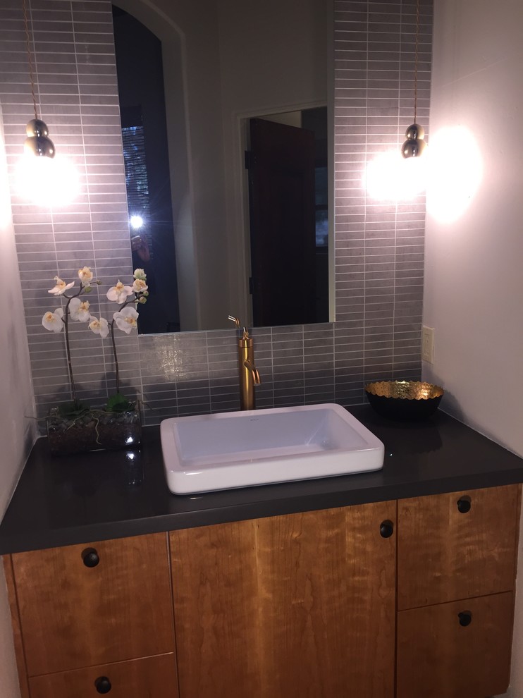 Photo of a mid-sized eclectic 3/4 bathroom in Phoenix with a vessel sink, flat-panel cabinets, medium wood cabinets, engineered quartz benchtops, an alcove tub, a shower/bathtub combo, a one-piece toilet, gray tile, porcelain tile, grey walls and porcelain floors.