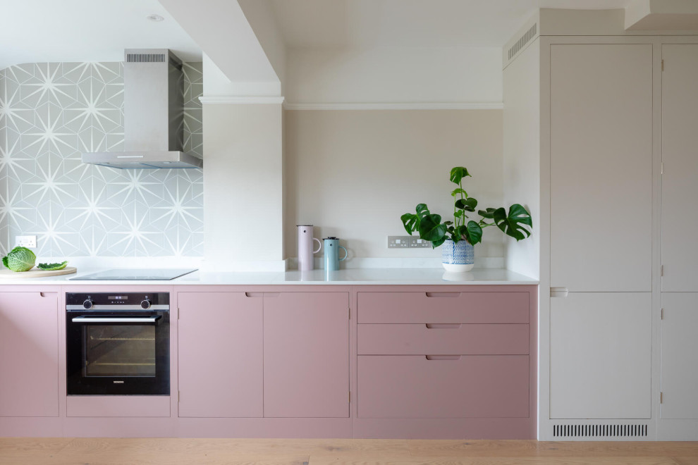 Mid-sized scandinavian l-shaped eat-in kitchen in Other with flat-panel cabinets, pink cabinets, quartz benchtops, light hardwood floors, no island and white benchtop.