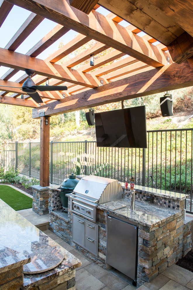 Design ideas for a mid-sized transitional backyard patio in Orange County with an outdoor kitchen, natural stone pavers and a pergola.