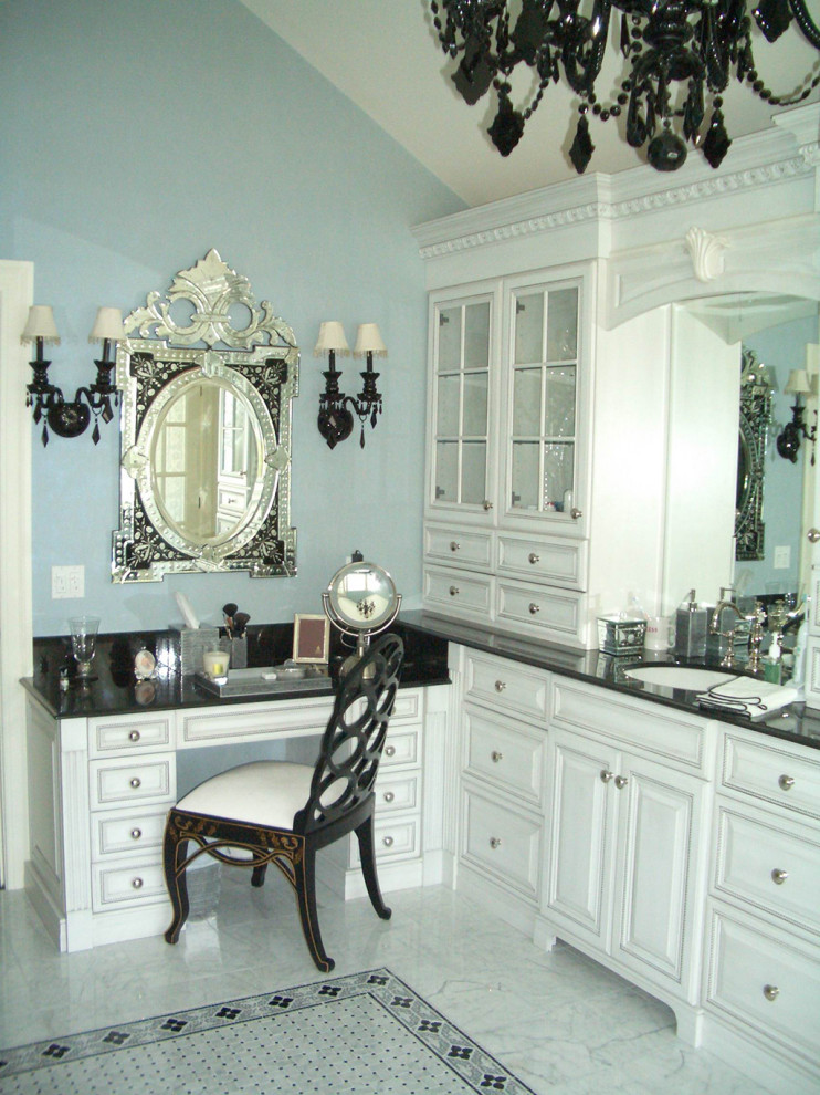 This is an example of a traditional master bathroom in New York with white cabinets, green walls, grey floor and black benchtops.