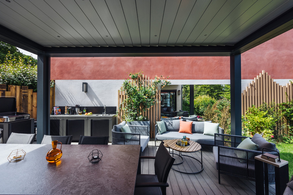 Modelo de terraza planta baja campestre grande en patio con cocina exterior, pérgola y barandilla de varios materiales