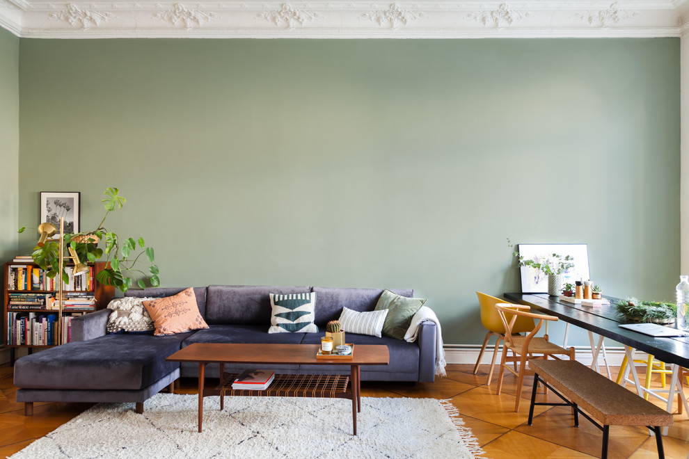 Eclectic open concept living room in Berlin with green walls and brown floor.