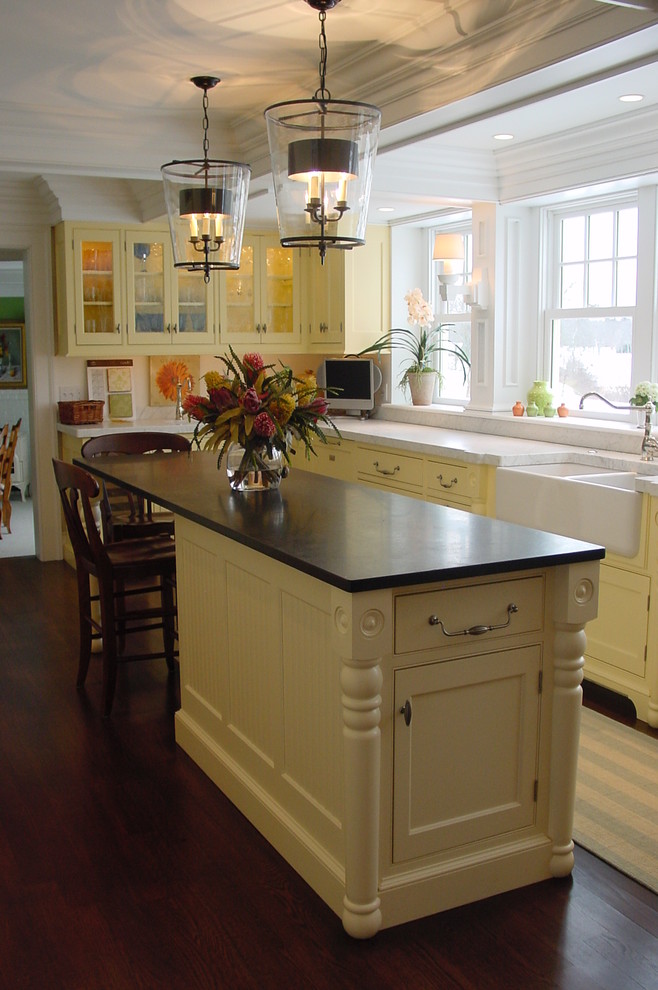 Inspiration for a large traditional l-shaped separate kitchen in Portland Maine with a farmhouse sink, beaded inset cabinets, yellow cabinets, marble benchtops, white splashback, stone slab splashback, panelled appliances, dark hardwood floors and with island.
