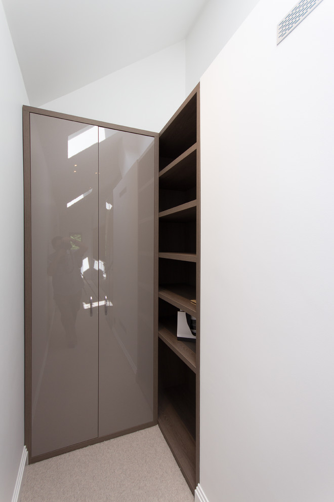 Photo of a large modern storage and wardrobe in London with carpet and beige floor.