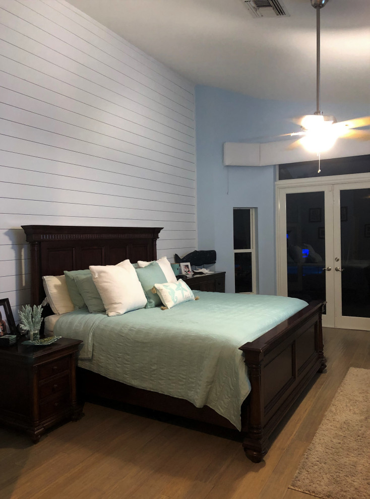 Foto di una camera matrimoniale minimal di medie dimensioni con pareti blu, pavimento in laminato, pavimento beige e pareti in perlinato