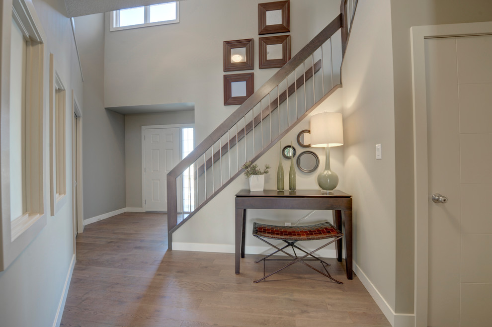 Example of a mid-sized transitional light wood floor and brown floor foyer design in Edmonton with gray walls and a gray front door