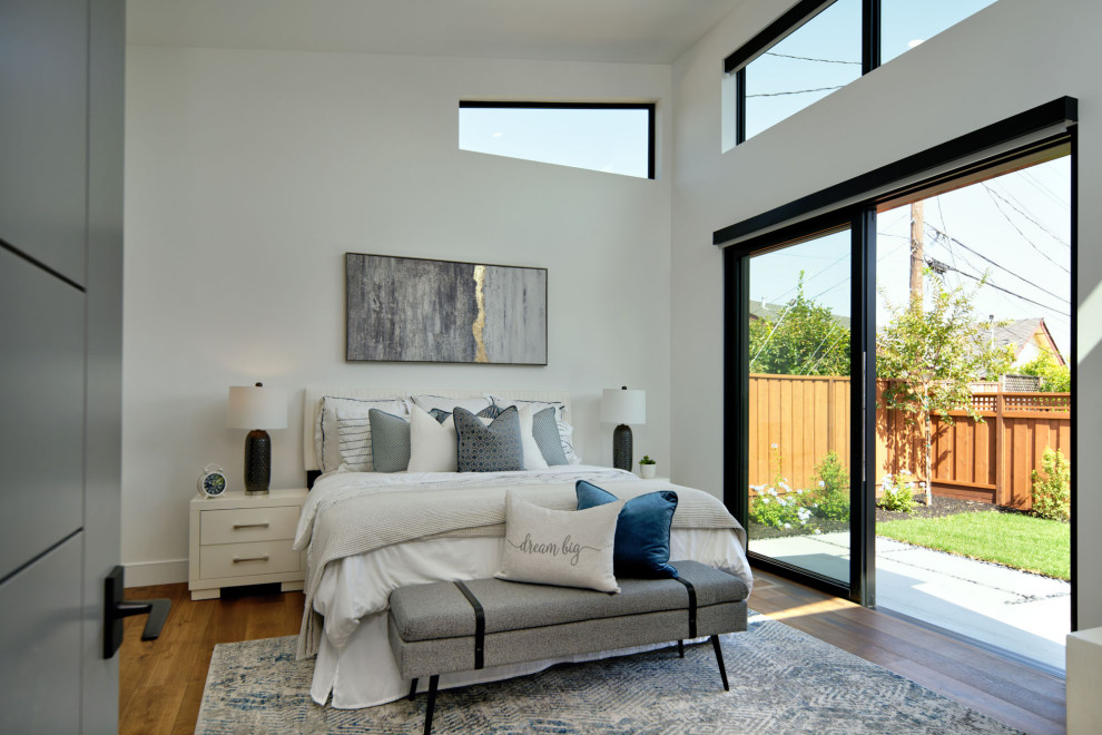 Large contemporary bedroom in San Francisco with white walls, medium hardwood floors, brown floor and vaulted.