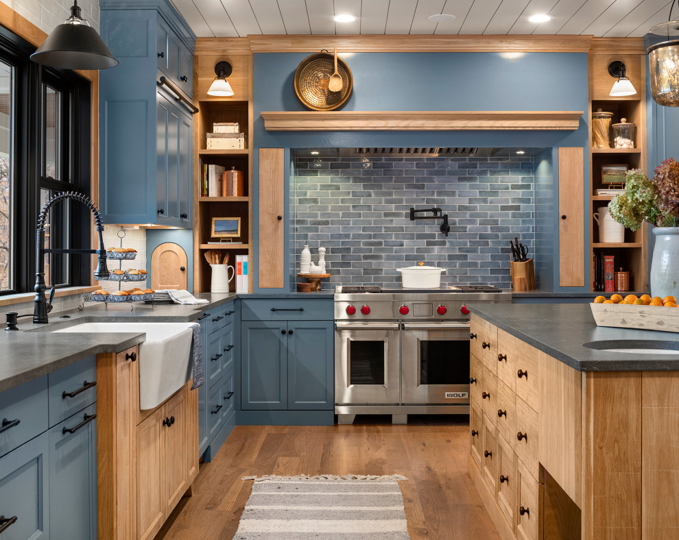 Design ideas for a large beach style u-shaped kitchen in Minneapolis with a belfast sink, recessed-panel cabinets, blue cabinets, quartz worktops, grey splashback, ceramic splashback, stainless steel appliances, medium hardwood flooring, an island, brown floors, grey worktops and a timber clad ceiling.