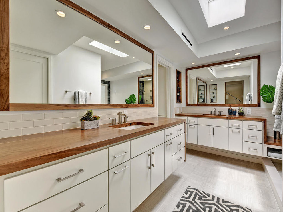 Inspiration for a mid-sized contemporary master bathroom in Austin with flat-panel cabinets, white cabinets, white tile, ceramic tile, white walls, ceramic floors, an undermount sink and wood benchtops.