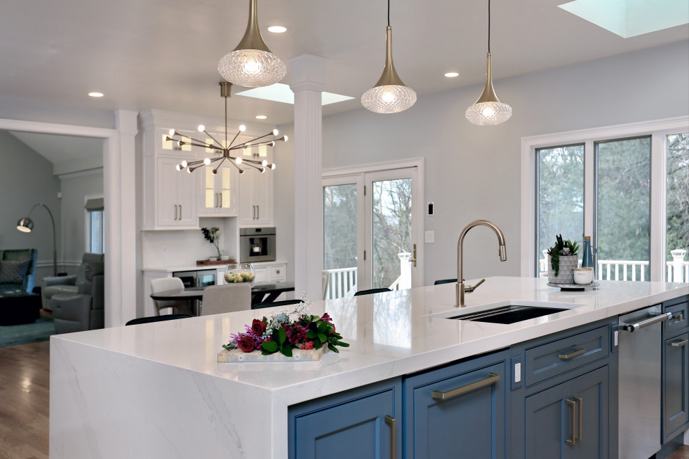 Photo of an expansive transitional u-shaped eat-in kitchen in Boston with an undermount sink, beaded inset cabinets, blue cabinets, quartz benchtops, white splashback, engineered quartz splashback, stainless steel appliances, medium hardwood floors, with island and white benchtop.