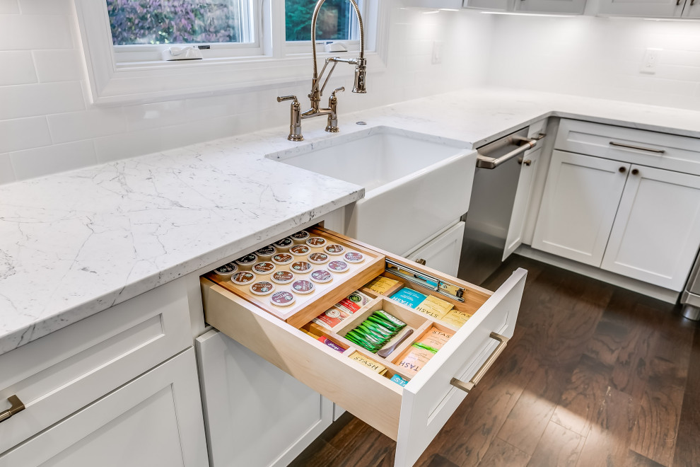 Mid-sized farmhouse l-shaped dark wood floor and brown floor eat-in kitchen photo in Baltimore with a farmhouse sink, shaker cabinets, white cabinets, marble countertops, white backsplash, ceramic backsplash, stainless steel appliances, an island and white countertops