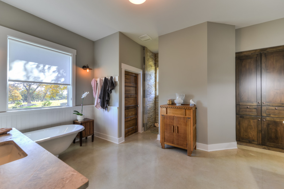 Large mountain style master multicolored tile and stone tile concrete floor claw-foot bathtub photo in Austin with recessed-panel cabinets, medium tone wood cabinets, a one-piece toilet, gray walls, an undermount sink and granite countertops