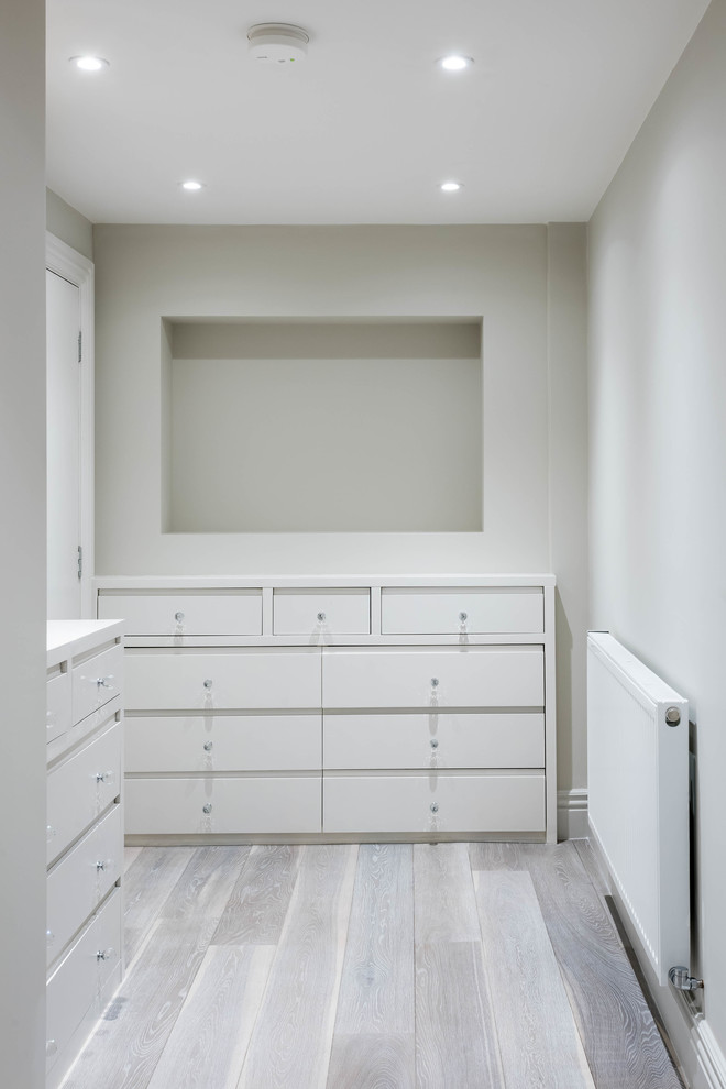 Mid-sized modern l-shaped laundry room in London with flat-panel cabinets, beige cabinets and light hardwood floors.